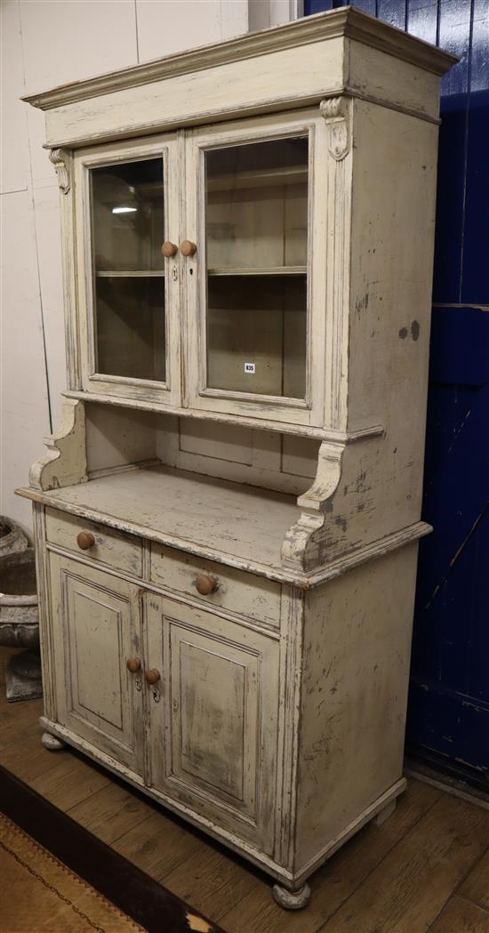 A pine dresser fitted a pair of glazed cupboards with distressed white-painted finish W.107cm